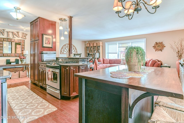 kitchen featuring stainless steel gas range oven, decorative light fixtures, light hardwood / wood-style flooring, a chandelier, and a kitchen island