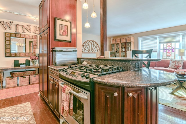 kitchen with stainless steel gas range oven, pendant lighting, a notable chandelier, dark stone countertops, and dark hardwood / wood-style floors