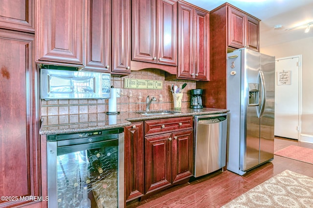 kitchen featuring sink, wine cooler, appliances with stainless steel finishes, light hardwood / wood-style floors, and light stone counters