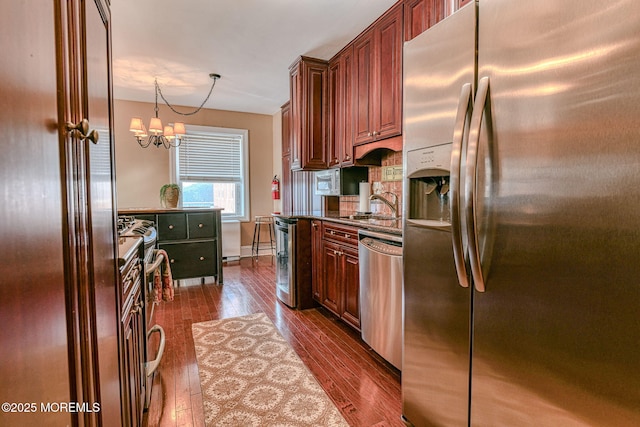 kitchen featuring dark wood-type flooring, sink, decorative light fixtures, a notable chandelier, and stainless steel appliances