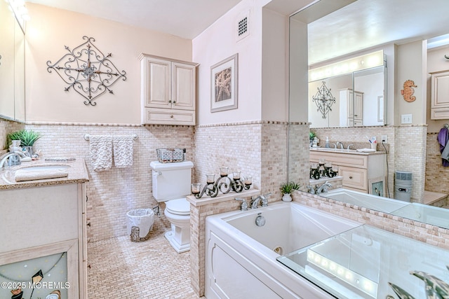 bathroom with vanity, tile patterned floors, a washtub, toilet, and tile walls