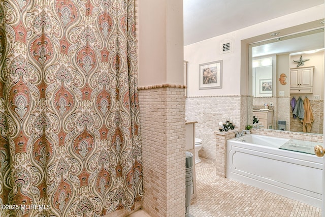 bathroom featuring tile patterned flooring, vanity, toilet, and tile walls