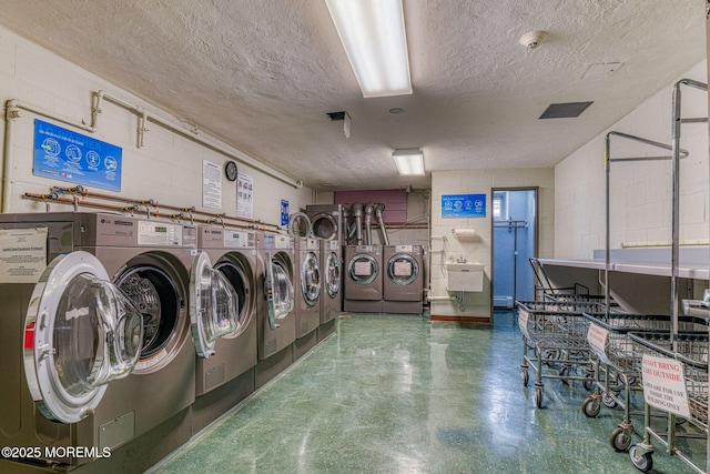 laundry area with separate washer and dryer, sink, and a textured ceiling