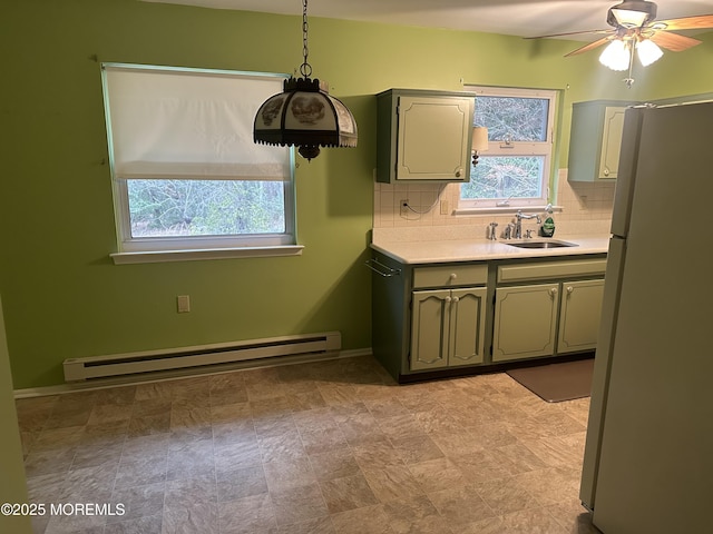 kitchen featuring ceiling fan, white refrigerator, decorative backsplash, sink, and a baseboard radiator