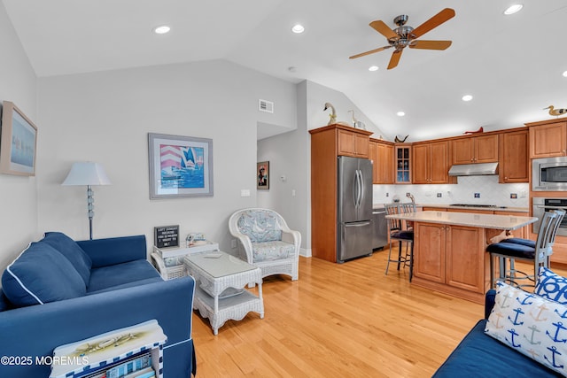 living room with light wood-type flooring, ceiling fan, and vaulted ceiling