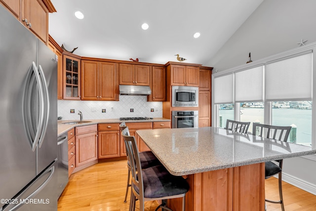 kitchen with vaulted ceiling, a breakfast bar area, stainless steel appliances, a center island, and sink