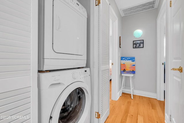 clothes washing area featuring stacked washer and dryer and light wood-type flooring