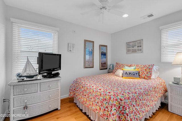 bedroom with ceiling fan, light hardwood / wood-style floors, and multiple windows