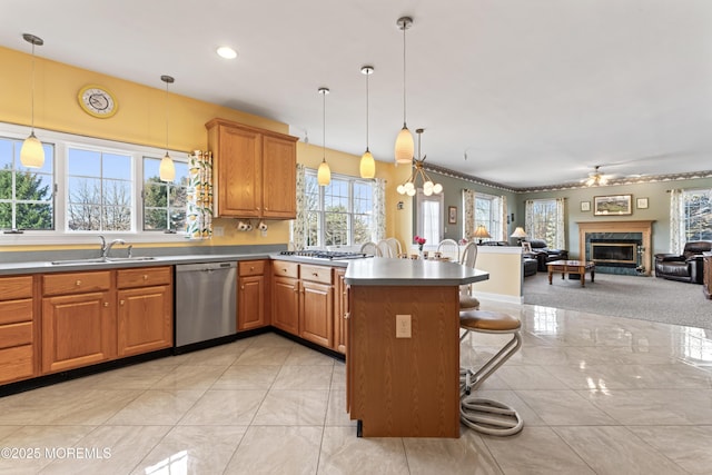 kitchen with stainless steel dishwasher, pendant lighting, a breakfast bar, ceiling fan, and sink