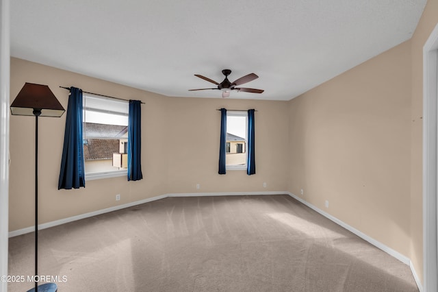 carpeted spare room with ceiling fan and plenty of natural light