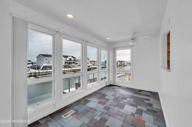 unfurnished sunroom featuring ceiling fan