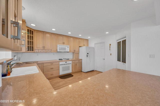 kitchen featuring sink, white appliances, light brown cabinetry, and light hardwood / wood-style floors