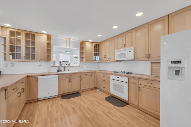 kitchen with sink, white appliances, light brown cabinets, and light wood-type flooring