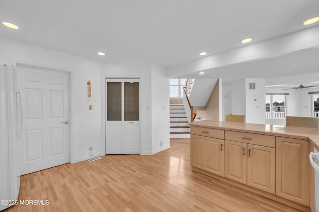 kitchen featuring ceiling fan, light brown cabinets, light hardwood / wood-style flooring, and white fridge