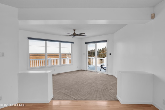 empty room with ceiling fan, light colored carpet, and beam ceiling