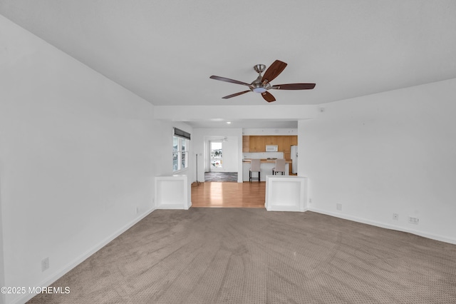 unfurnished living room featuring ceiling fan and light carpet