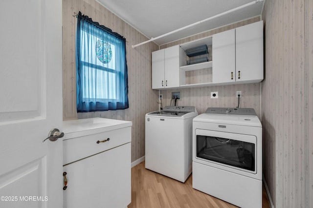 clothes washing area with cabinets, light hardwood / wood-style flooring, and separate washer and dryer