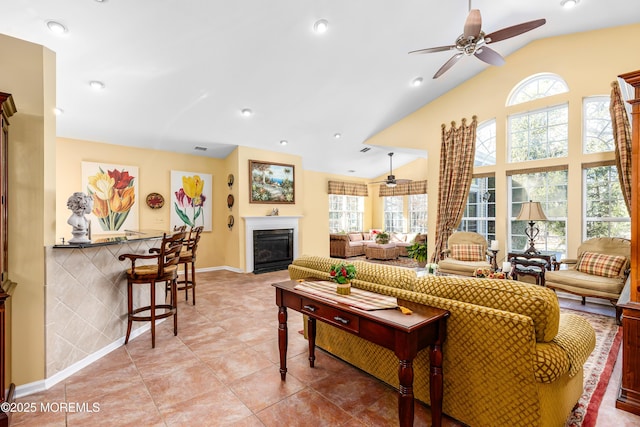 tiled living room with ceiling fan and vaulted ceiling