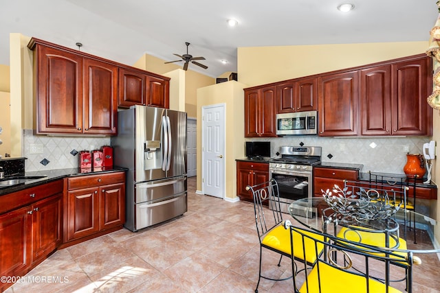 kitchen with light tile patterned floors, ceiling fan, appliances with stainless steel finishes, backsplash, and vaulted ceiling