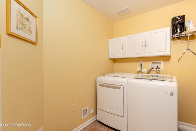 laundry area with washing machine and dryer, tile patterned floors, and cabinets