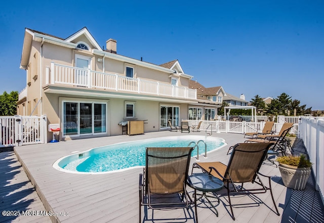 rear view of property featuring a pool side deck and a balcony