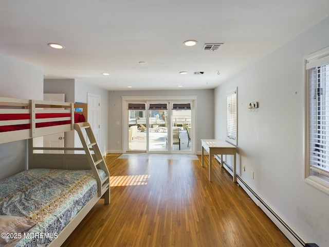 bedroom featuring baseboard heating, wood-type flooring, and access to outside