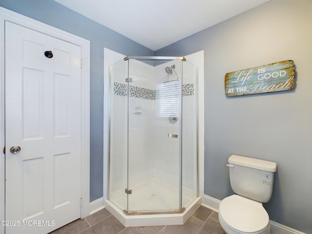 bathroom with tile patterned flooring, a shower with door, and toilet