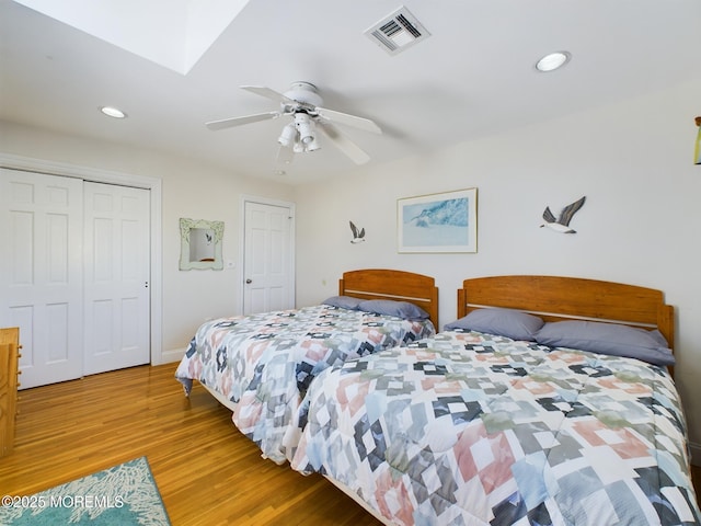 bedroom with ceiling fan, a skylight, a closet, and light wood-type flooring