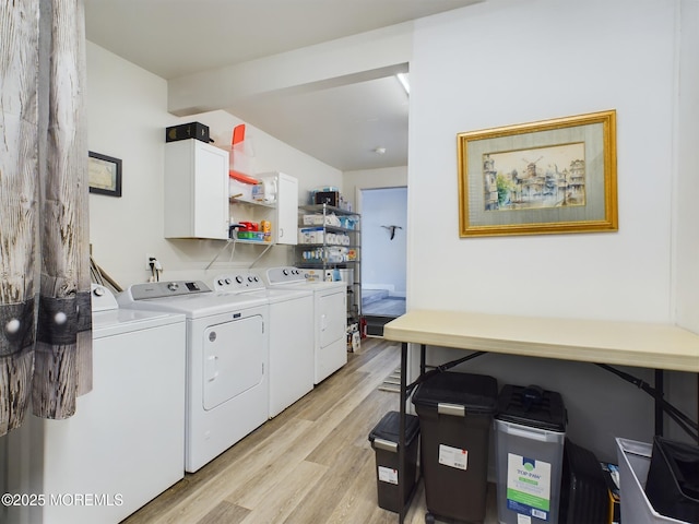 laundry area with cabinets, washing machine and dryer, and light hardwood / wood-style flooring