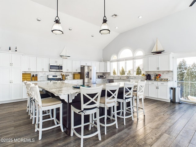 kitchen featuring a large island, hanging light fixtures, white cabinets, and appliances with stainless steel finishes