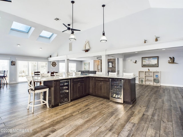 kitchen featuring wine cooler, a large island, hanging light fixtures, and dark brown cabinets