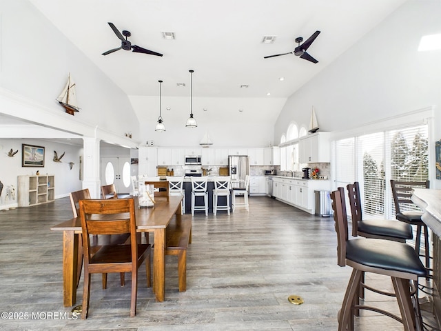 dining area with ceiling fan, dark hardwood / wood-style floors, and high vaulted ceiling