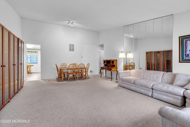 living room featuring a towering ceiling and light carpet