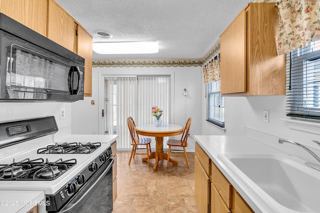 kitchen featuring range with gas cooktop, a textured ceiling, and sink