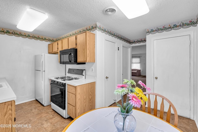 kitchen featuring white appliances, light brown cabinetry, and a textured ceiling