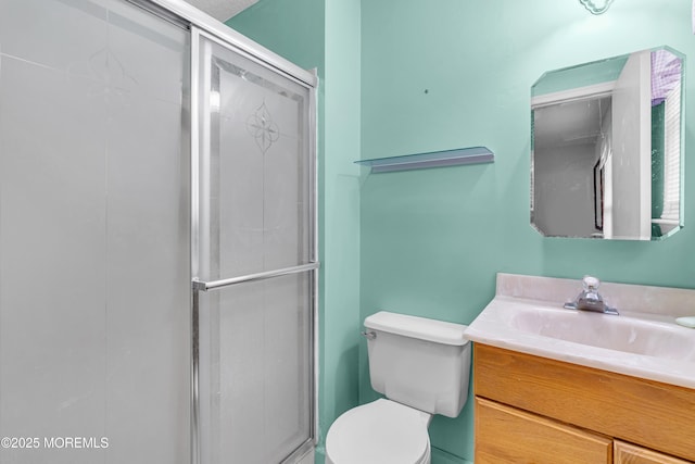 bathroom featuring toilet, a shower with door, and vanity