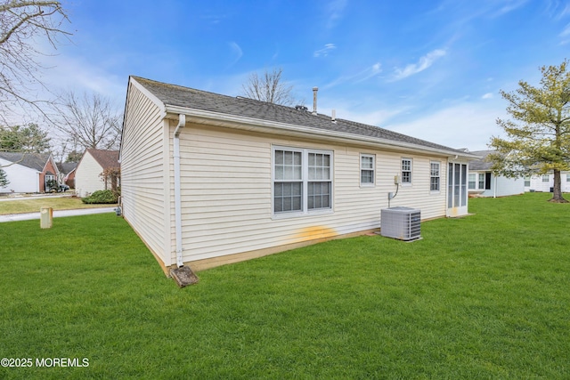 back of house with central air condition unit and a lawn