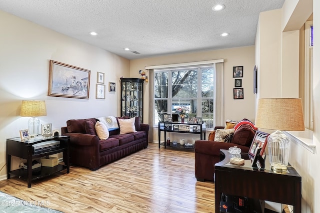 living room with a textured ceiling and light wood-type flooring