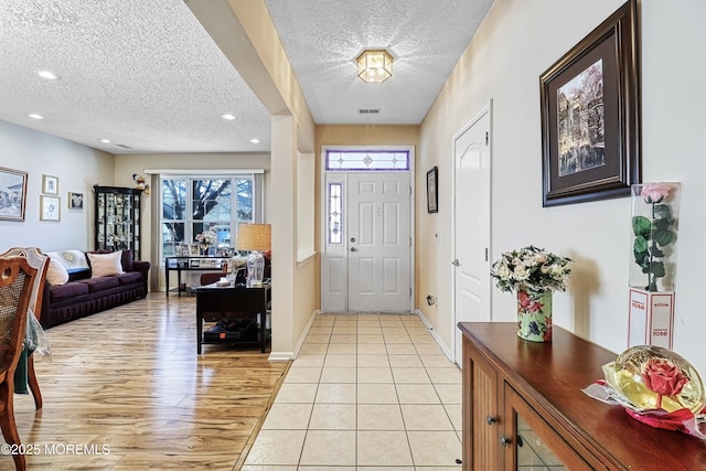 entryway with a textured ceiling and light tile patterned floors