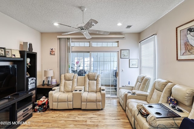 living room featuring a textured ceiling, ceiling fan, and light wood-type flooring