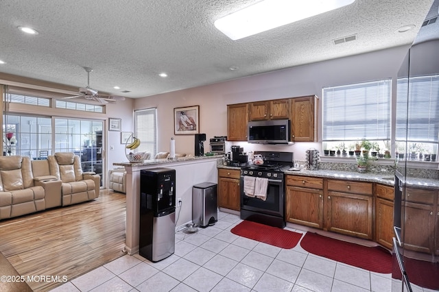 kitchen featuring gas range oven, a textured ceiling, and light tile patterned flooring