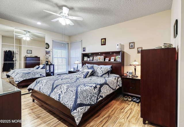 bedroom with a textured ceiling, ceiling fan, and light hardwood / wood-style flooring