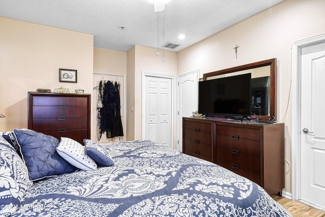 bedroom with light hardwood / wood-style floors, ceiling fan, and a textured ceiling