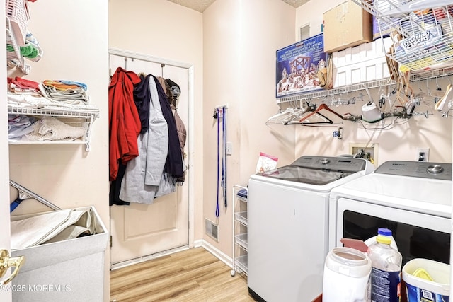 laundry area featuring washing machine and dryer and light hardwood / wood-style floors