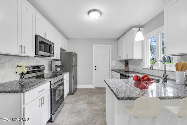 kitchen featuring kitchen peninsula, pendant lighting, stainless steel appliances, and white cabinetry