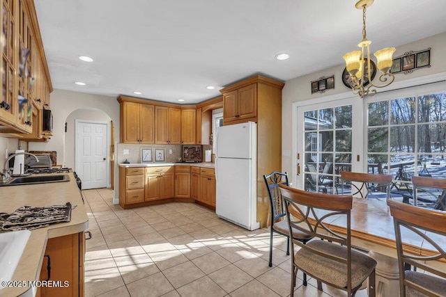 kitchen featuring light tile patterned floors, sink, an inviting chandelier, hanging light fixtures, and white refrigerator