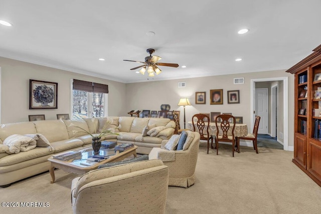 living room with light carpet, ornamental molding, and ceiling fan