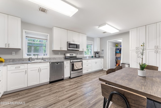 kitchen with white cabinets, light wood-type flooring, stainless steel appliances, and sink