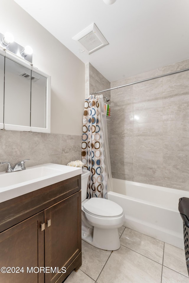 full bathroom with shower / tub combo, tile patterned flooring, toilet, vanity, and tile walls