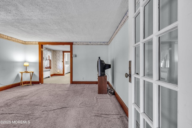 hallway with light colored carpet, a textured ceiling, and radiator